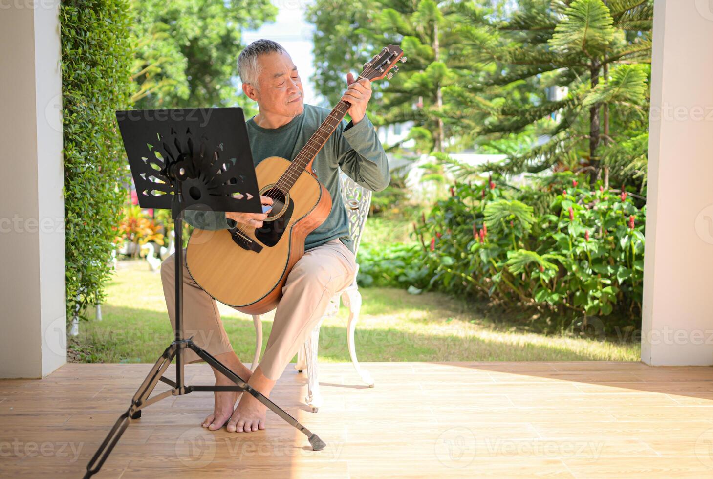 Senior man a veteran guitarist plays music in the garden at home photo