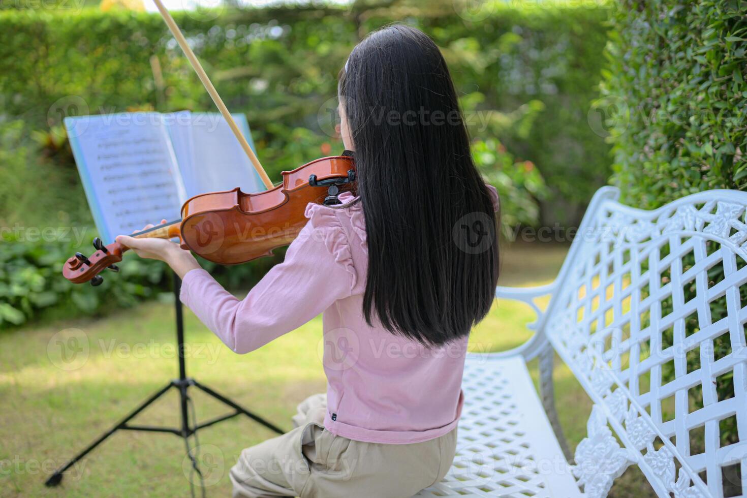 A girl violinist plays and practices the violin in the garden at home photo