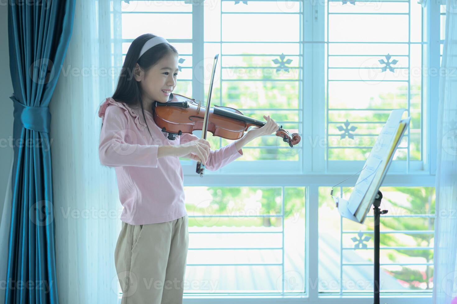 A girl violinist plays and practices the violin at home photo