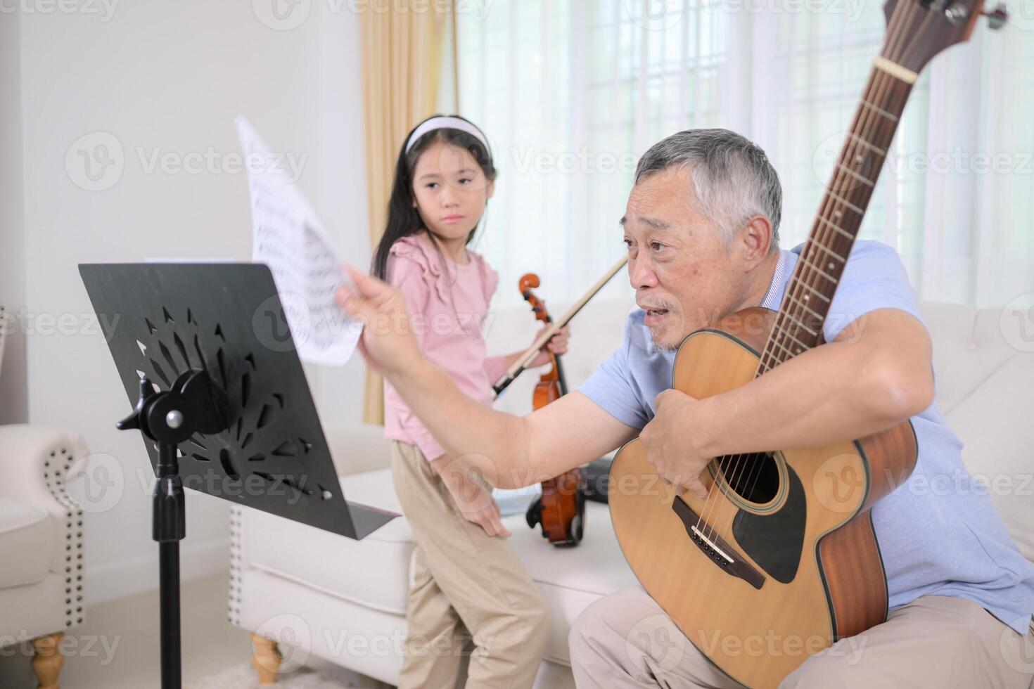 A girl violinist and her grandfather practice music together at home photo