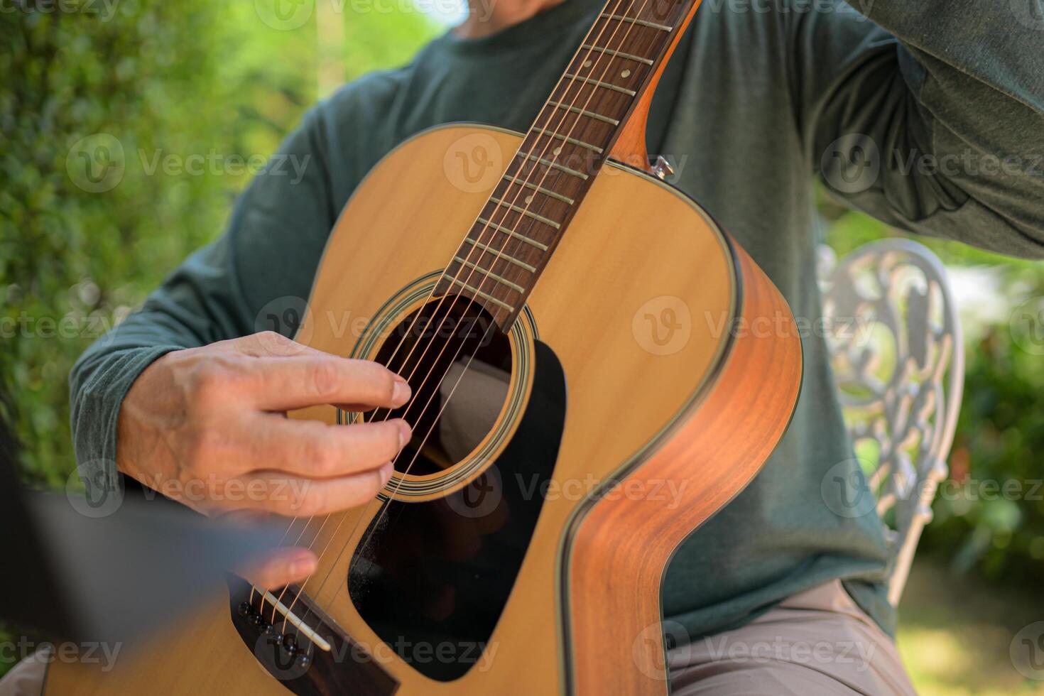 Senior man a veteran guitarist plays music in the garden at home photo