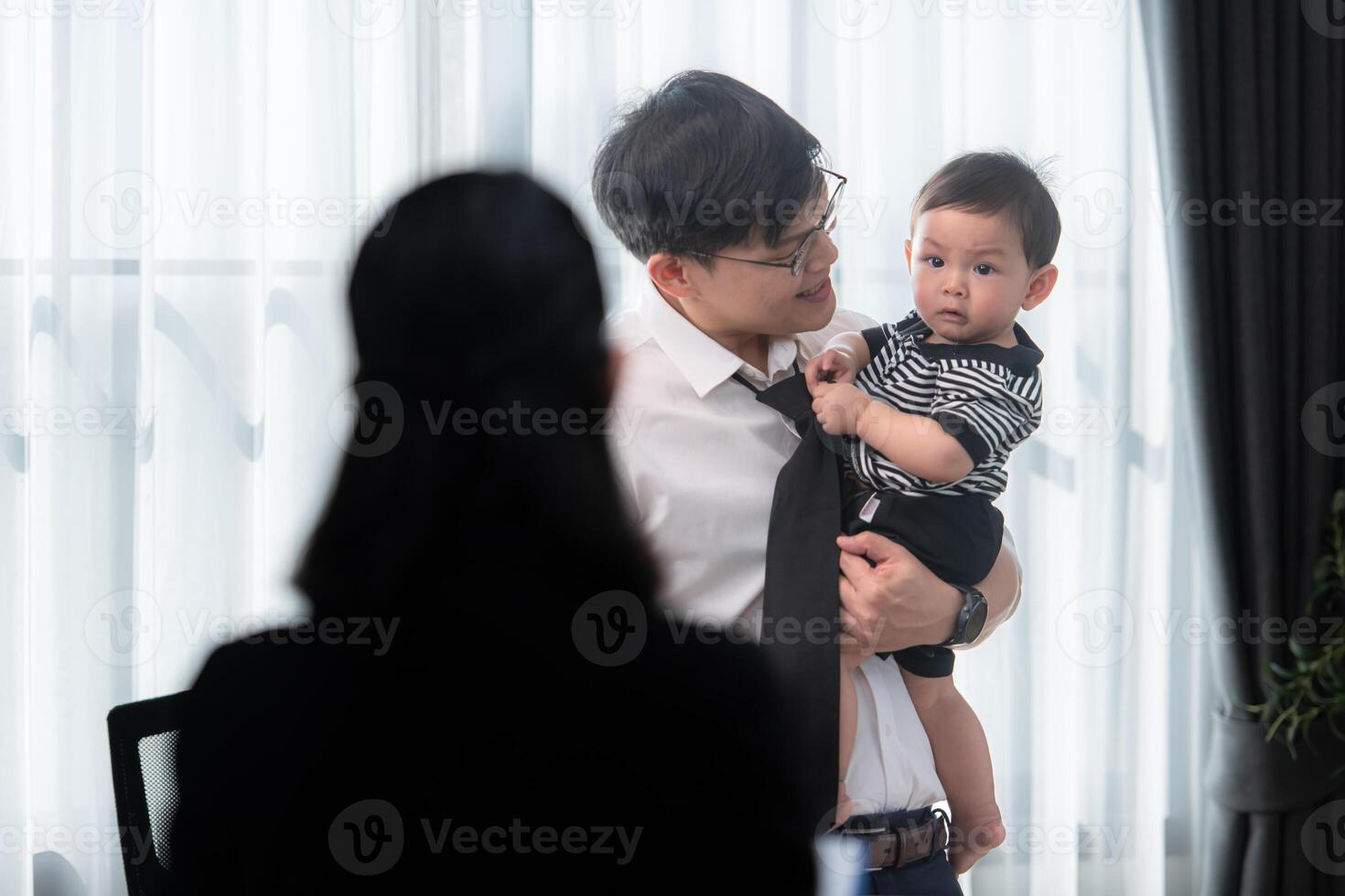 A business father assigns work to his secretary, while also taking care of his child while working photo