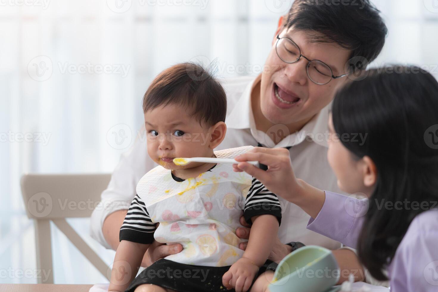Father and mother feed their son breakfast before going to work in the kitchen of the house photo