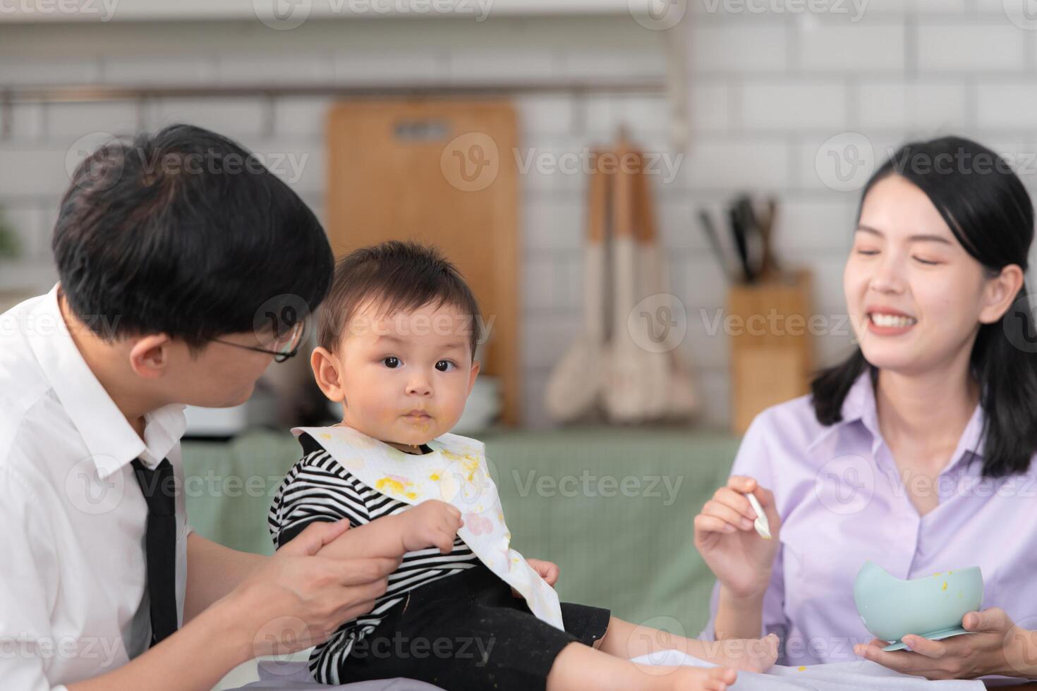 Father and mother feed their son breakfast before going to work in the kitchen of the house photo