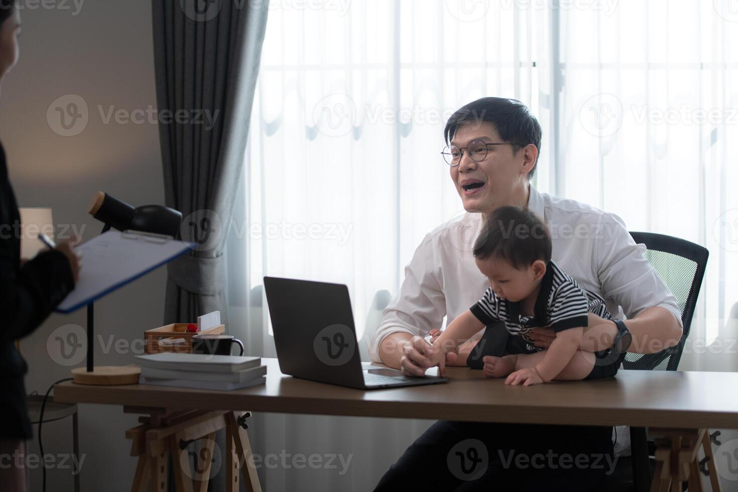 A business father assigns work to his secretary, while also taking care of his child while working photo