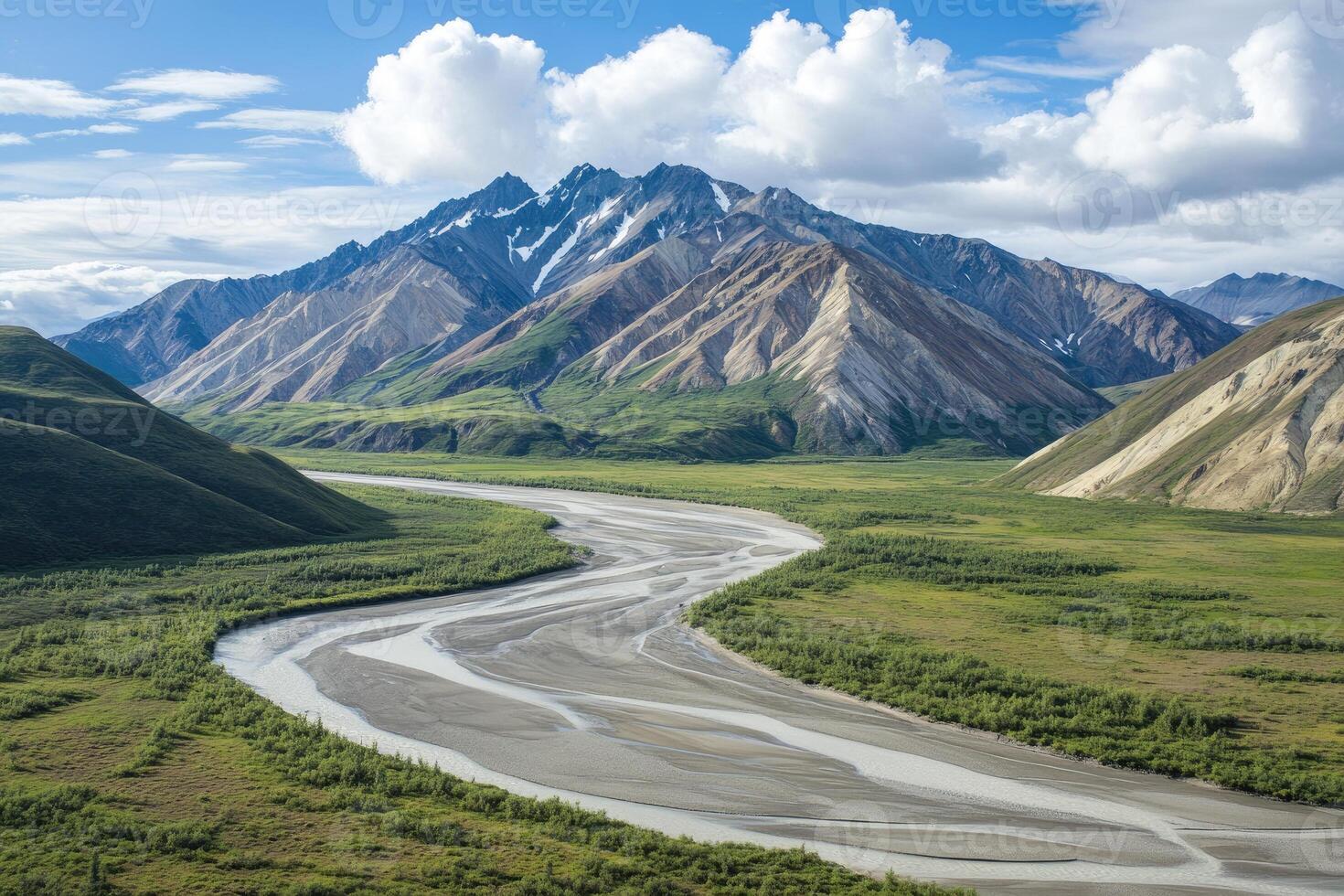 A winding river flows through a valley surrounded by snow-capped mountains. photo