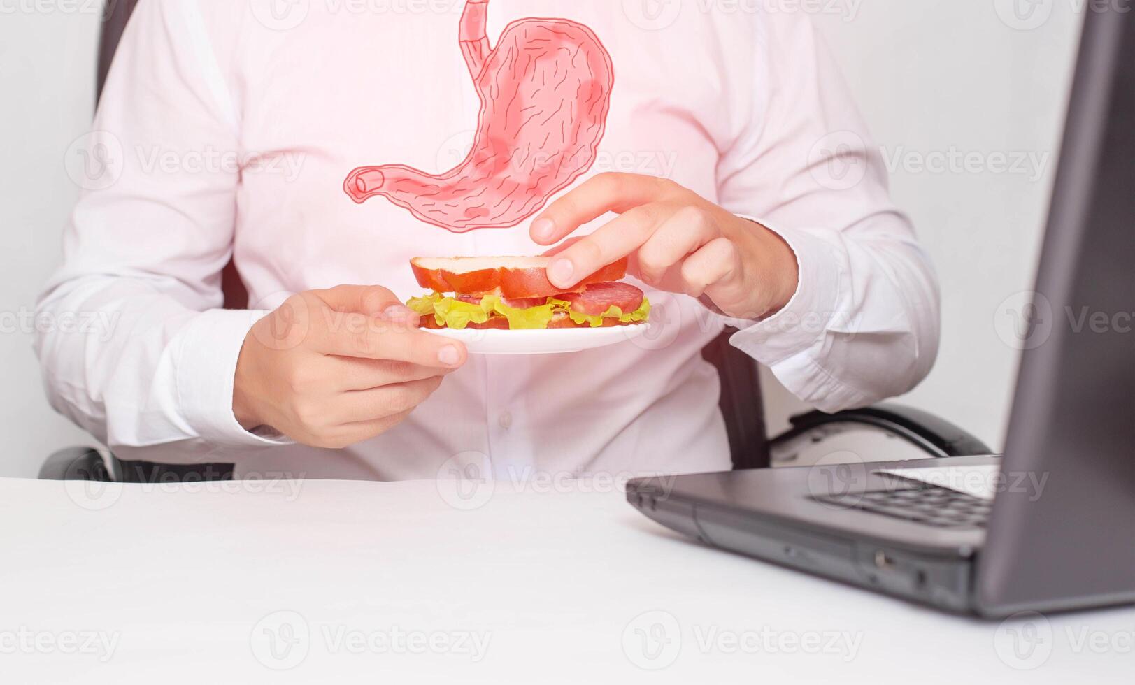 A male office worker holds a sandwich in his hands during lunch. The concept of unhealthy food, snacking, stomach pain. Gastritis and heartburn photo