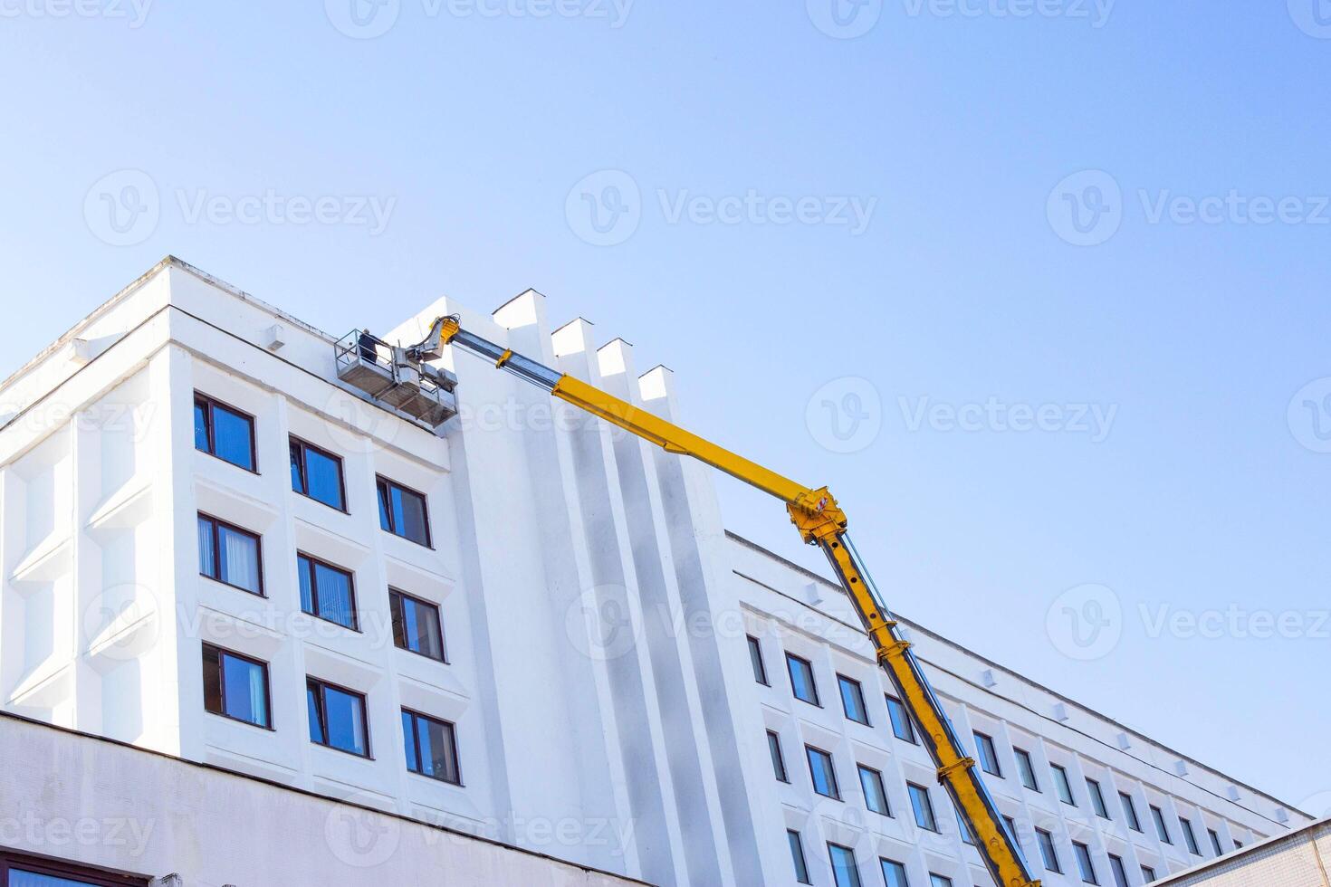 Repair and reconstruction of the facade of the building with the help of a worker and a car tower. Blue sky industry, copy space photo