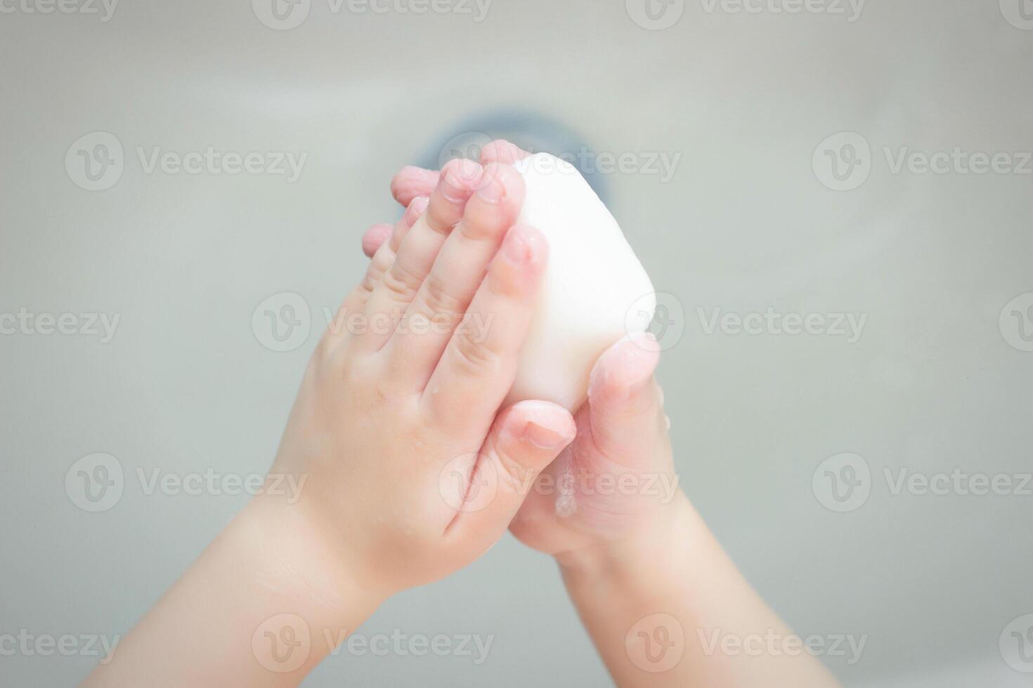 A child washes his hands with soap in the bathroom. The concept of hygiene and clean hands, infection, close-up, soundness photo