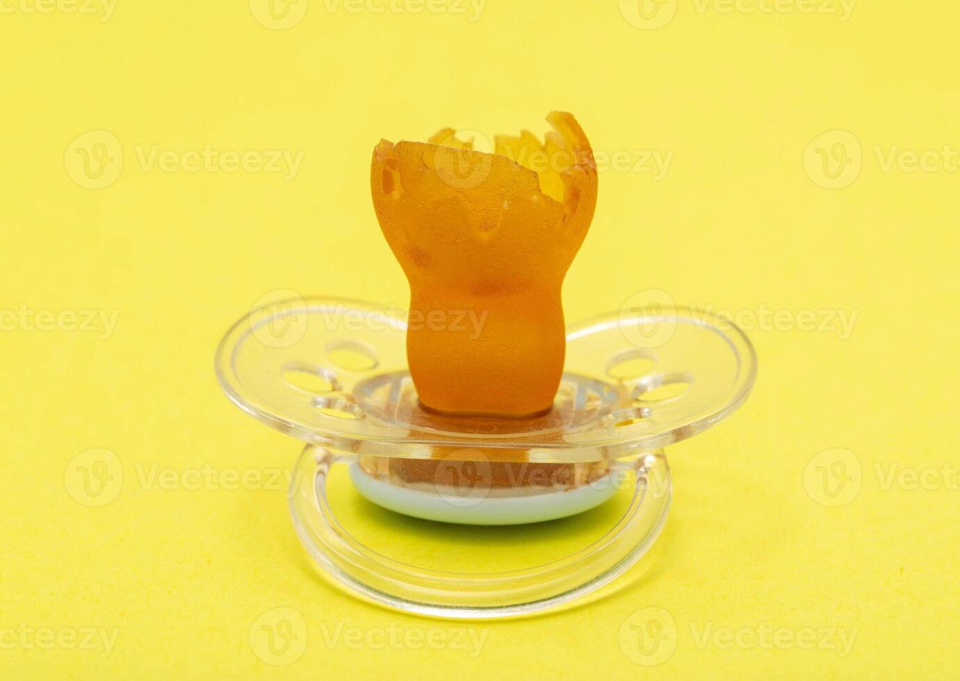 Low-quality torn baby silicone pacifier on a yellow background, close-up. Concept of the anatomical shape of the pacifier, teething in children. photo