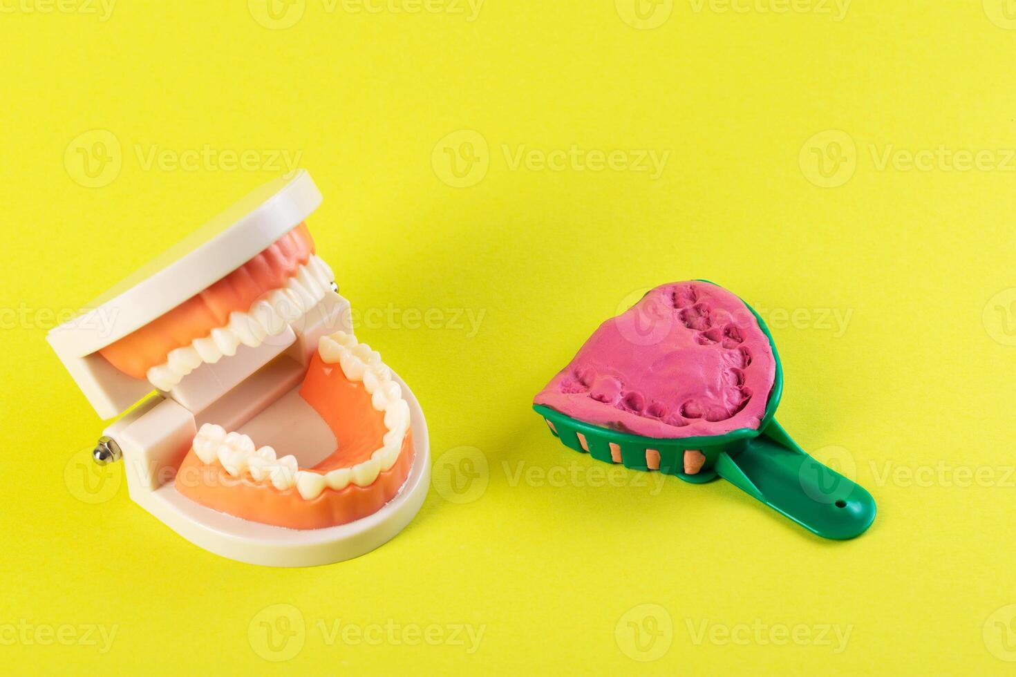 Green dental spoon for taking a dental impression in a mock-up of a dental jaw on a yellow background. Making an artificial jaw for malocclusion. Manufacturing of dental prostheses photo