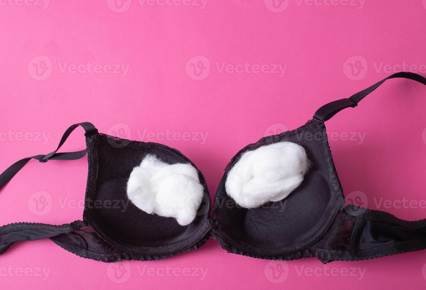 black female bra with cotton wool inside on a pink background. The concept of augmentation of the female breast with plastic surgery, mammoplasty photo