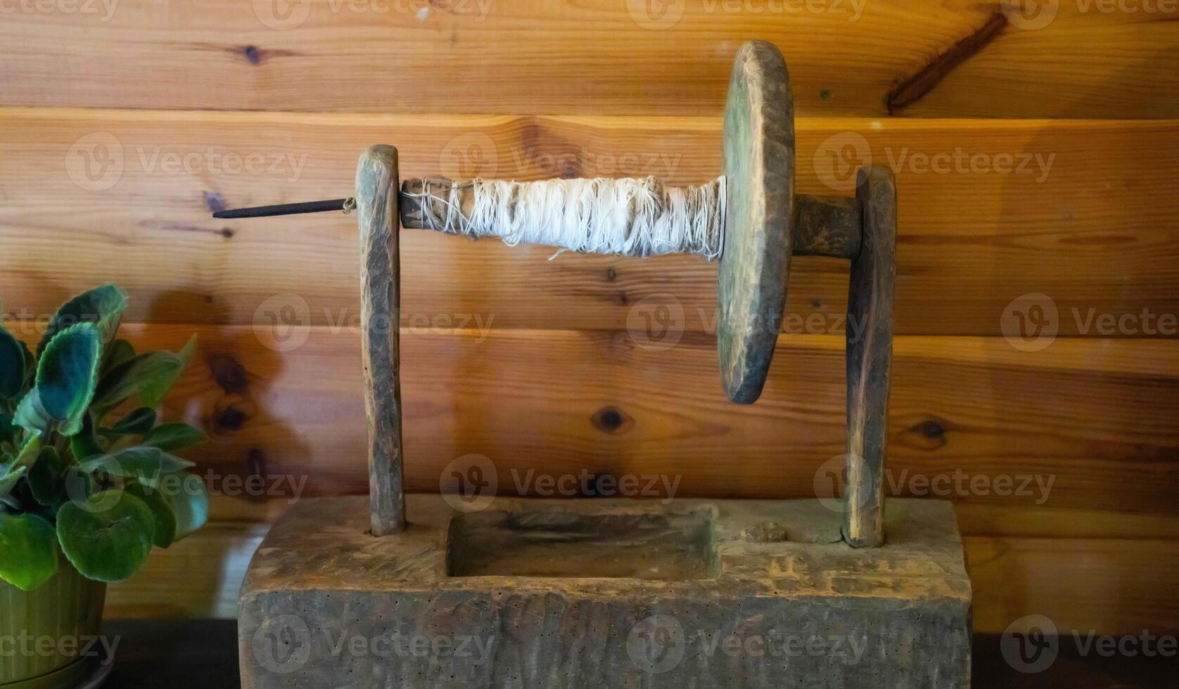 Antique device for winding thread on a spool on a wooden background. Production of threads and fabrics in the last century. Tradicional photo