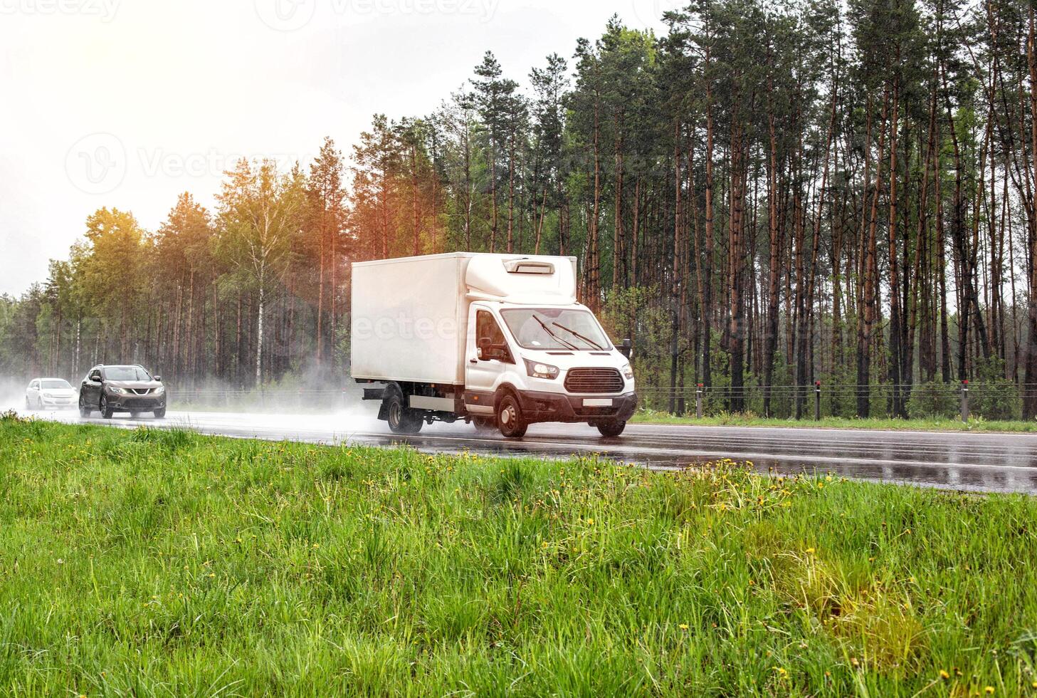 Refrigerated van transports perishable cargo of confectionery. The truck drives on a wet highway in rainy weather. Copy space for text photo