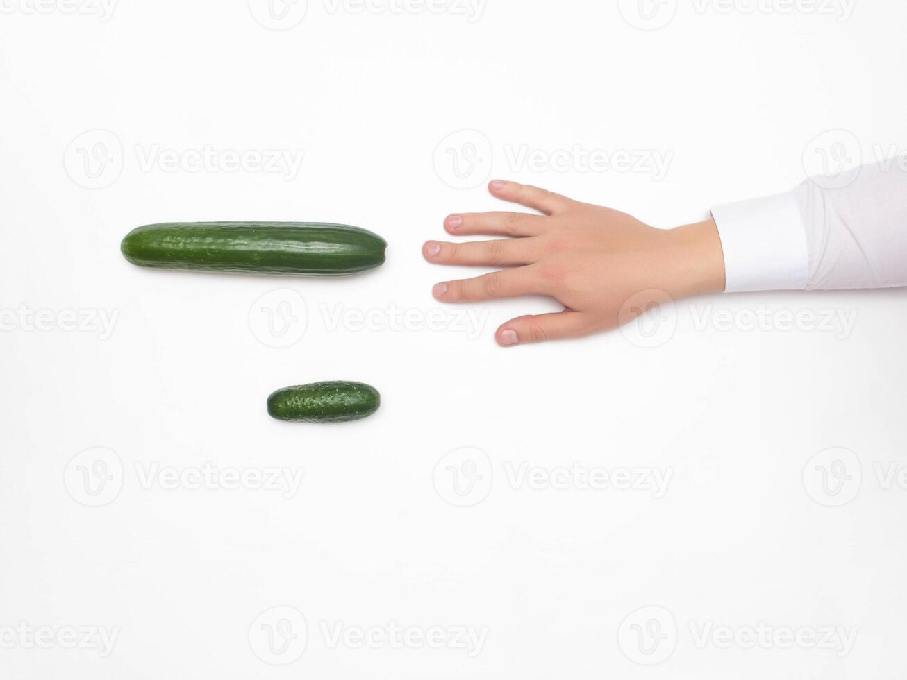 Male hand on a white background reaching for a big cucumber, the concept of increasing the male penis using different techniques, medical, copy space, erection photo
