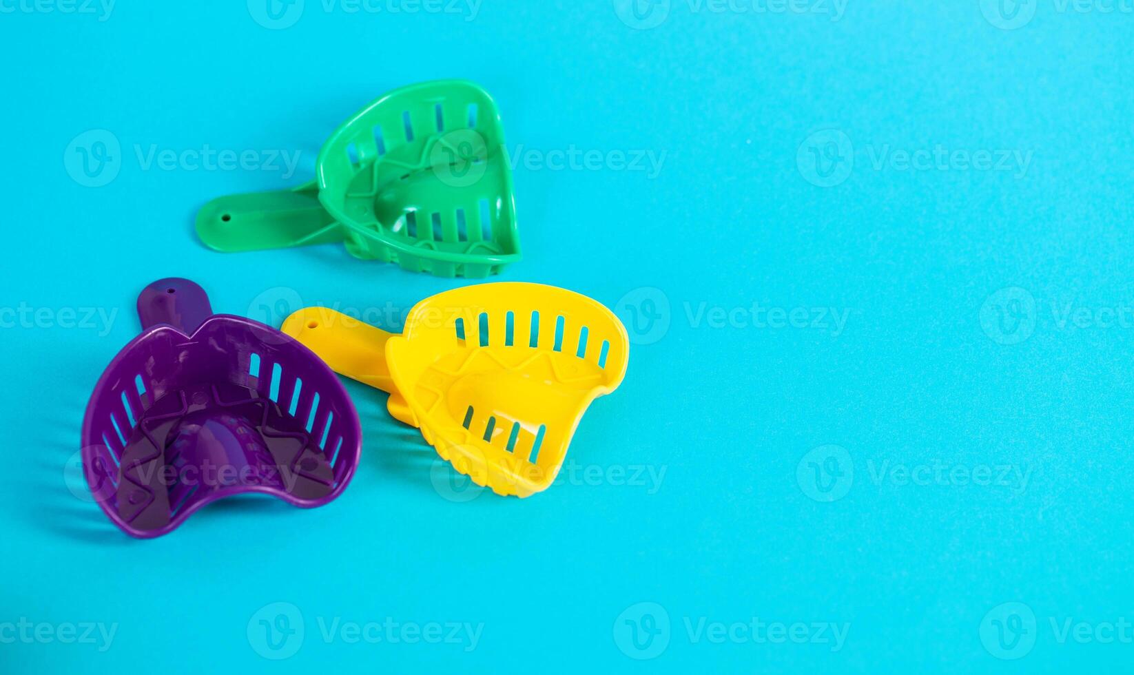 Multi-colored dental spoons for taking an impression of the dental jaw on a blue background. Making an impression of the jaw for braces and dental prosthetics, close-up. Copy space for text photo