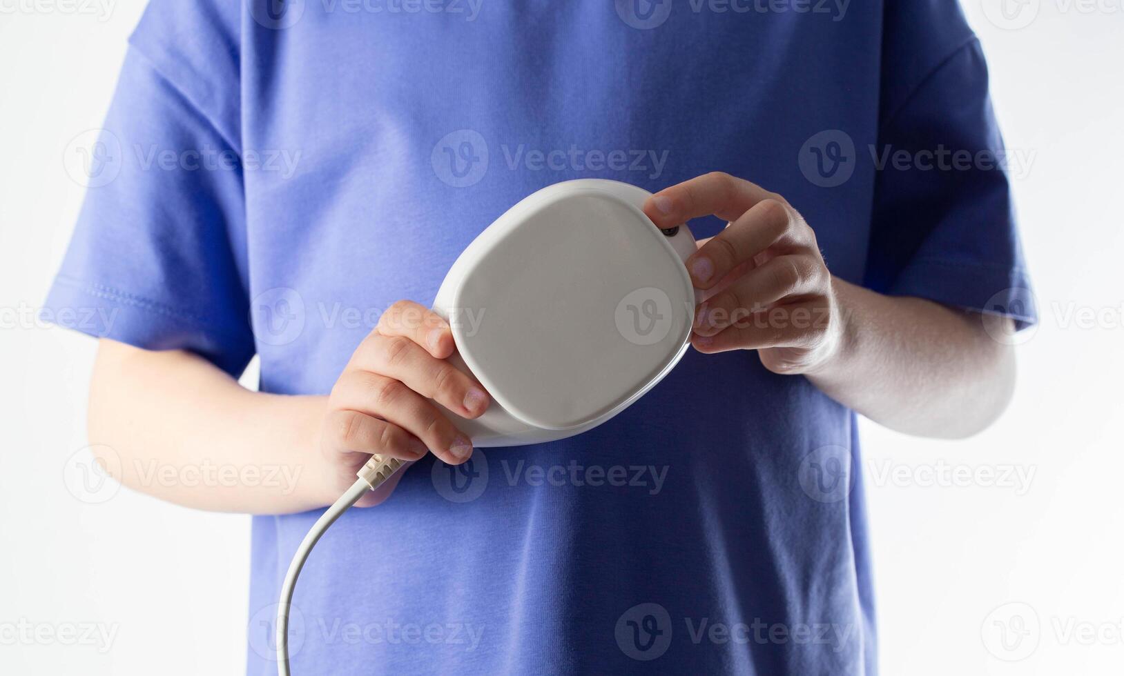 A child holds in his hands a low-frequency portable magnetic therapy device for the restoration and treatment of diseases, close-up. Home physiotherapy, magnetotherapy photo