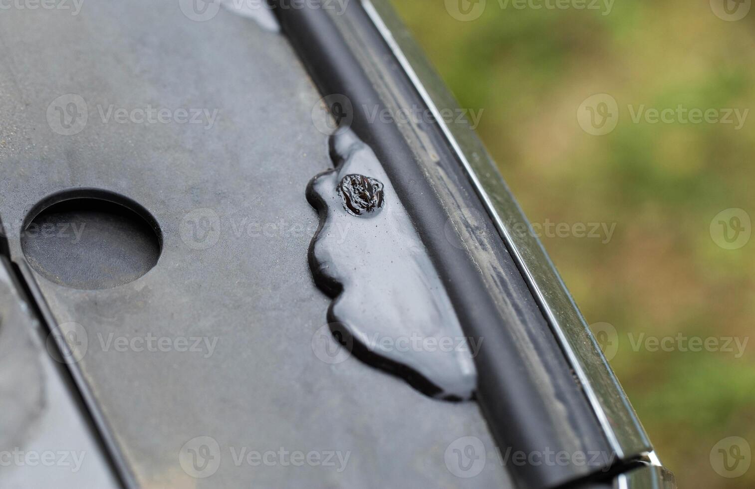 Anti-corrosive leakage in the engine compartment after treatment with an anti-corrosion coating on the car, protecting metal from corrosion, close-up photo