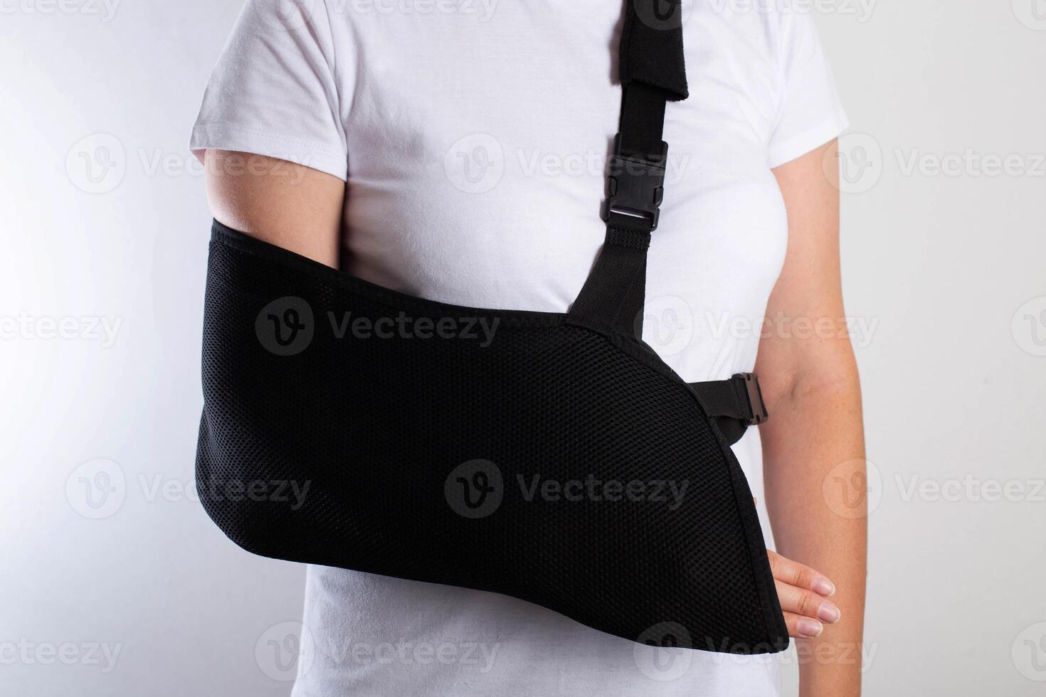 A girl in white with a black support bandage for her arm after a fracture of the ulna. Damage to ulnar ligaments, arm fracture. Trauma, rehabilitation, hand immobilization photo