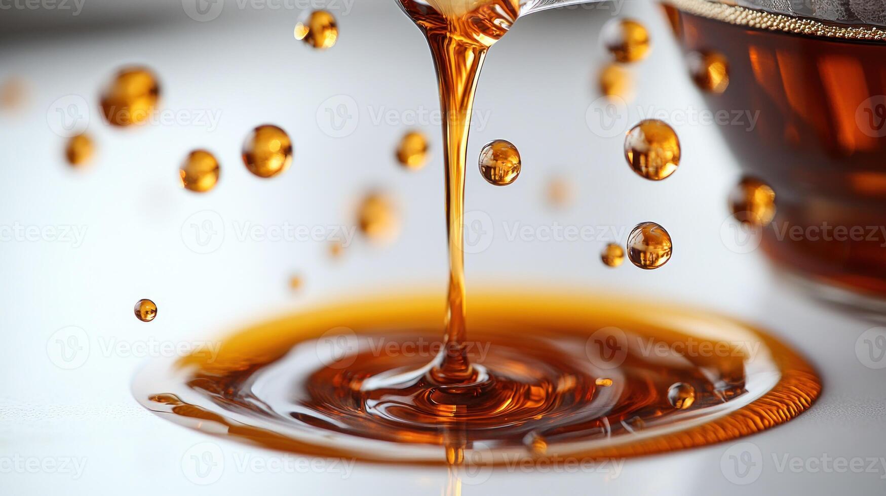 Golden syrup drips gracefully from a spoon into a shimmering pool on a table photo
