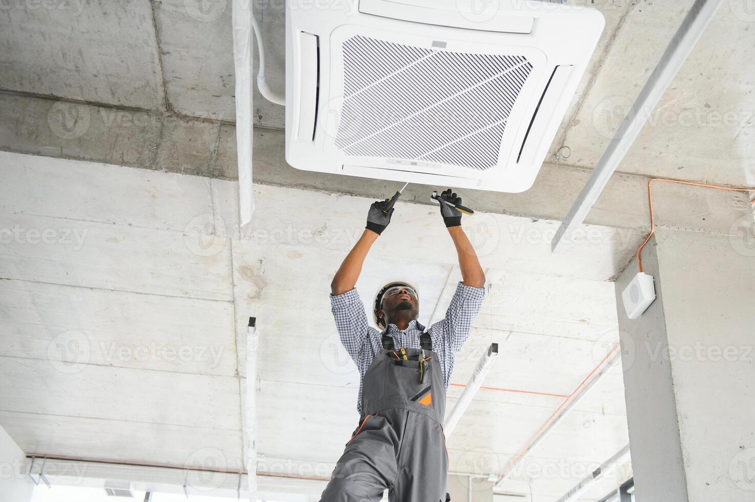 Happy Young African Male Technician Repairing Air Conditioner photo