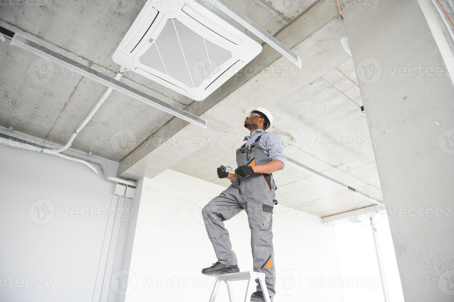 low angle view of african american handyman repairing air conditioner photo