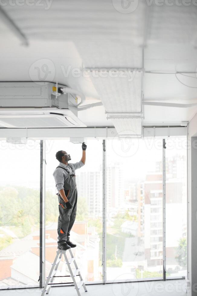 African HVAC Technician Worker Testing Newly Installed Ventilation System. Commercial Heating, Cooling and Air Ventilation Systems photo