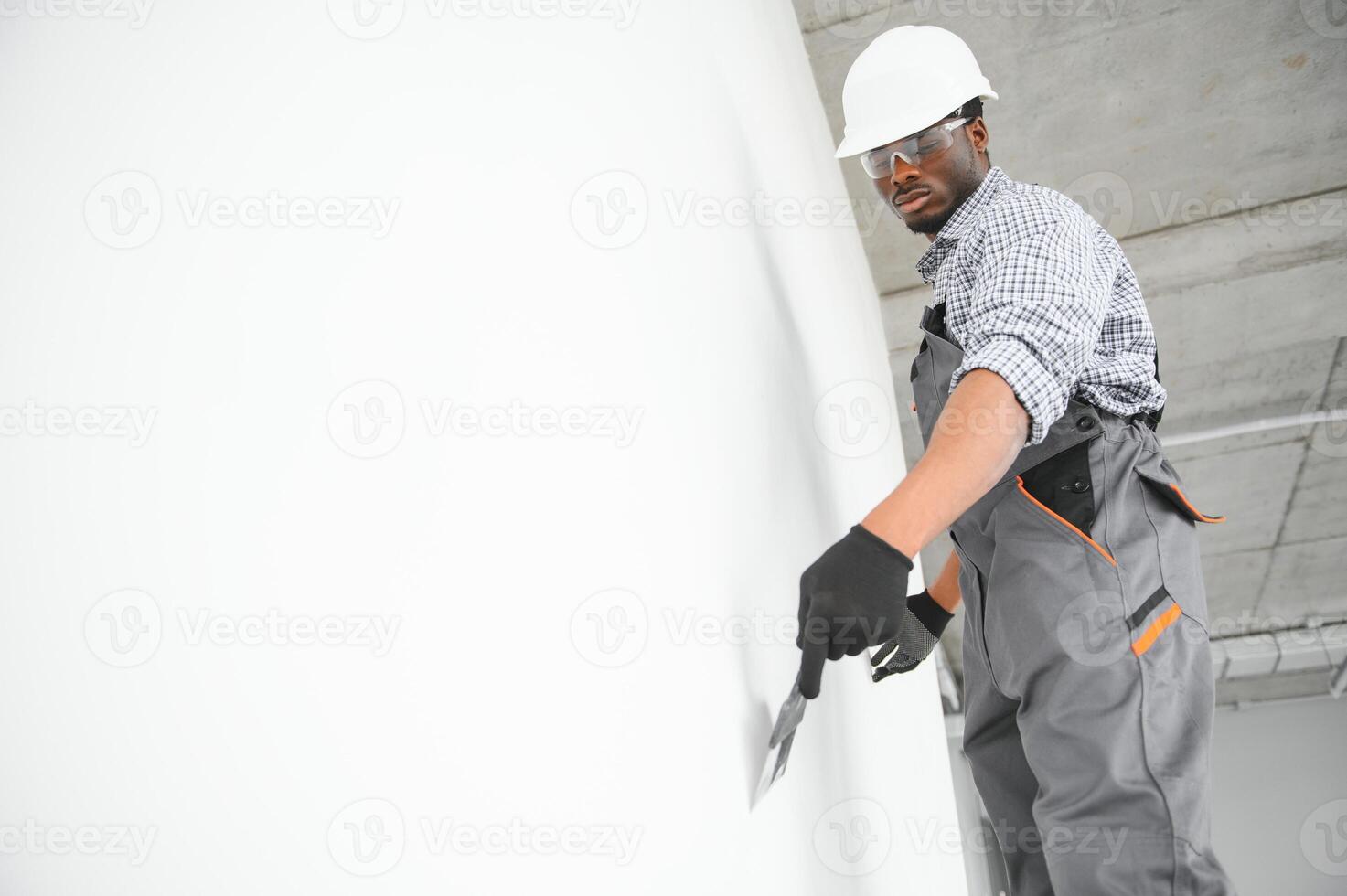 business, building, and people concept. african builder in hardhats with plastering tools indoors photo