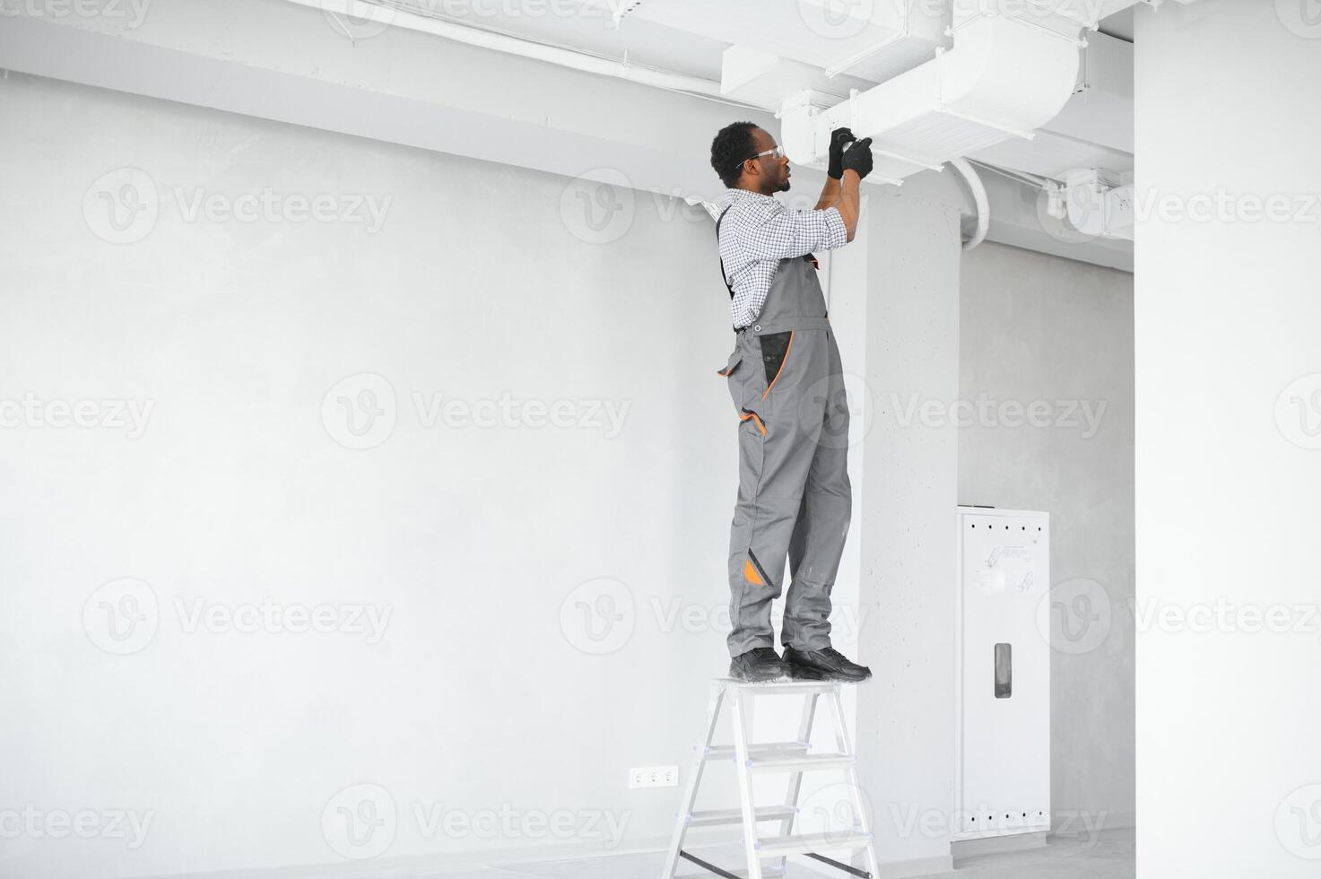 African HVAC Technician Worker Testing Newly Installed Ventilation System. Commercial Heating, Cooling and Air Ventilation Systems photo