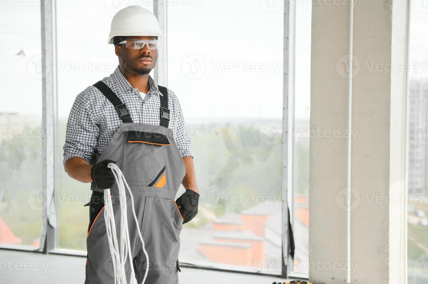 An African electrician stands on a construction site with a cable in his hands photo