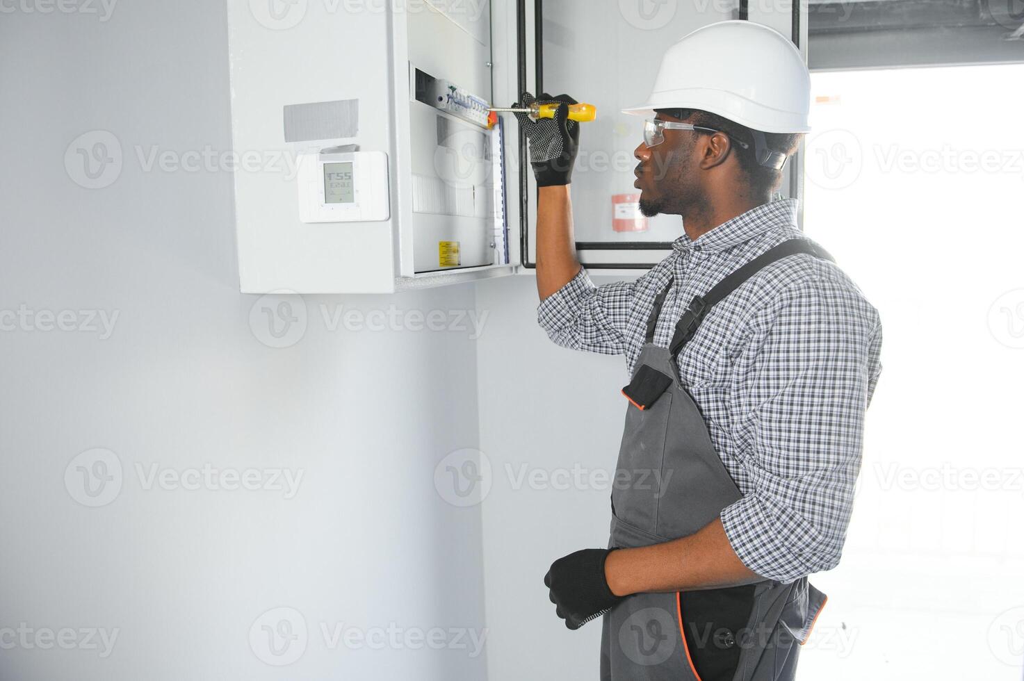 A male electrician works in a switchboard photo