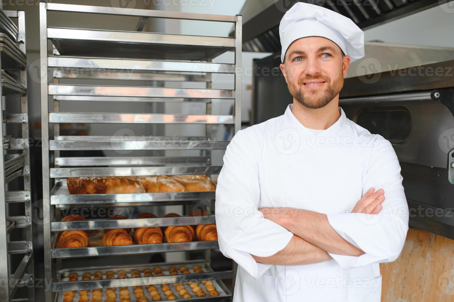 Happy baker standing near tray with bread at the bakery photo