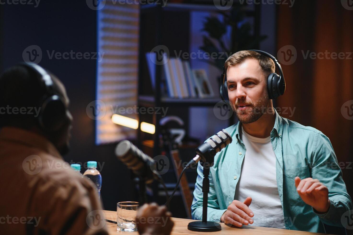 Show host and guest meeting to stream podcast episode together, creating online content with live broadcast discussion. Vlogger talking to man using professional equipment to record chat photo