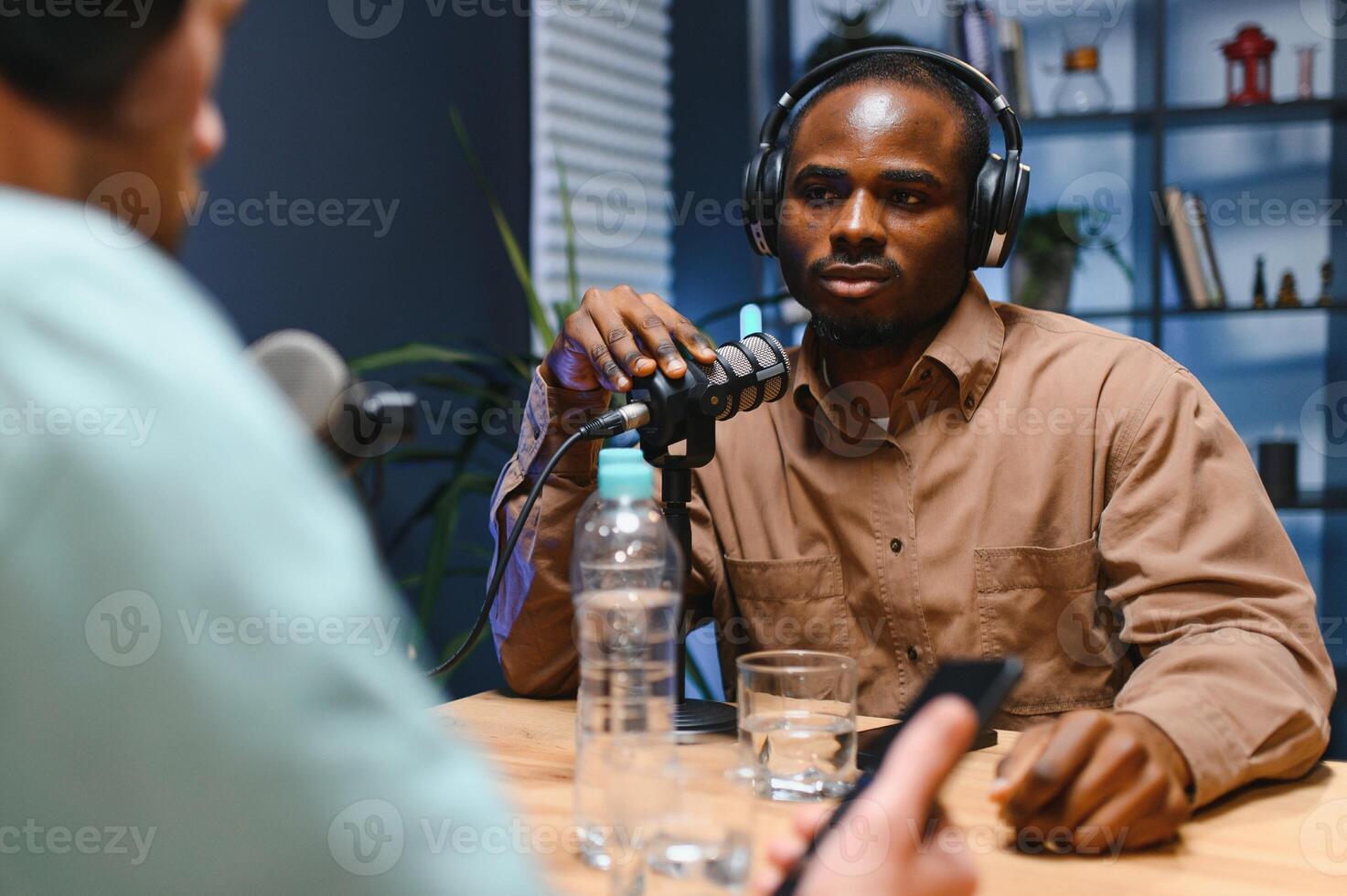 Man recording podcast using high tech microphones to interview guest, ensuring flawless and sound quality for audience photo