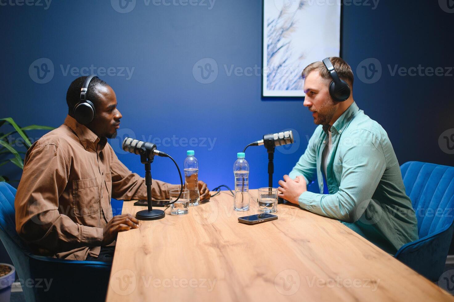 Show host and guest meeting to stream podcast episode together, creating online content with live broadcast discussion. Vlogger talking to man using professional equipment to record chat photo