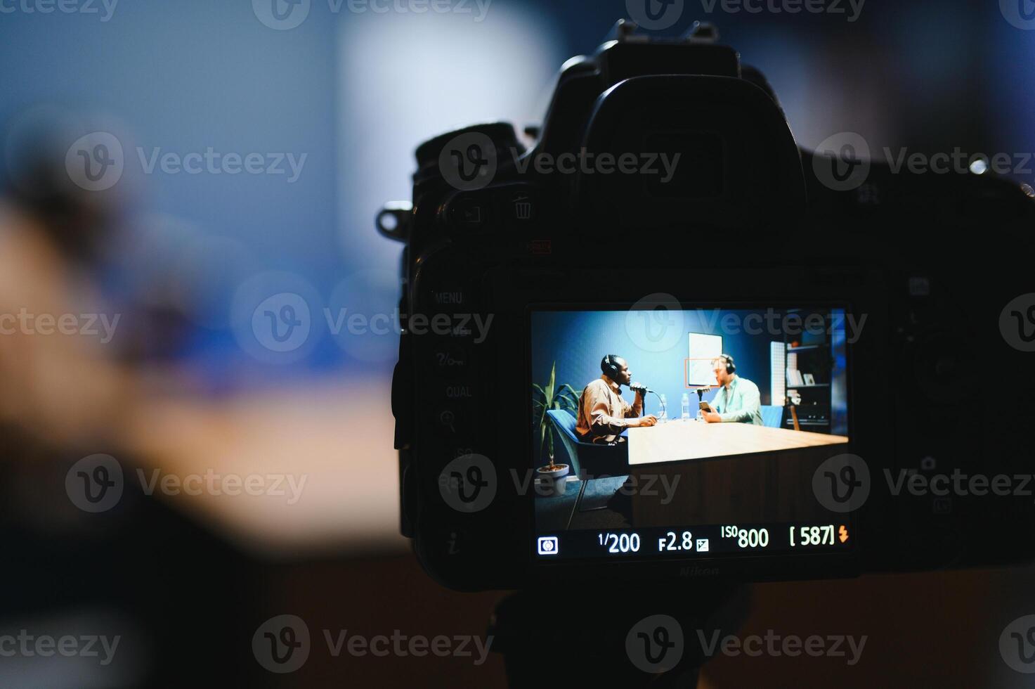 Focus on the camera filming the men's podcast in a professional podcast studio. photo