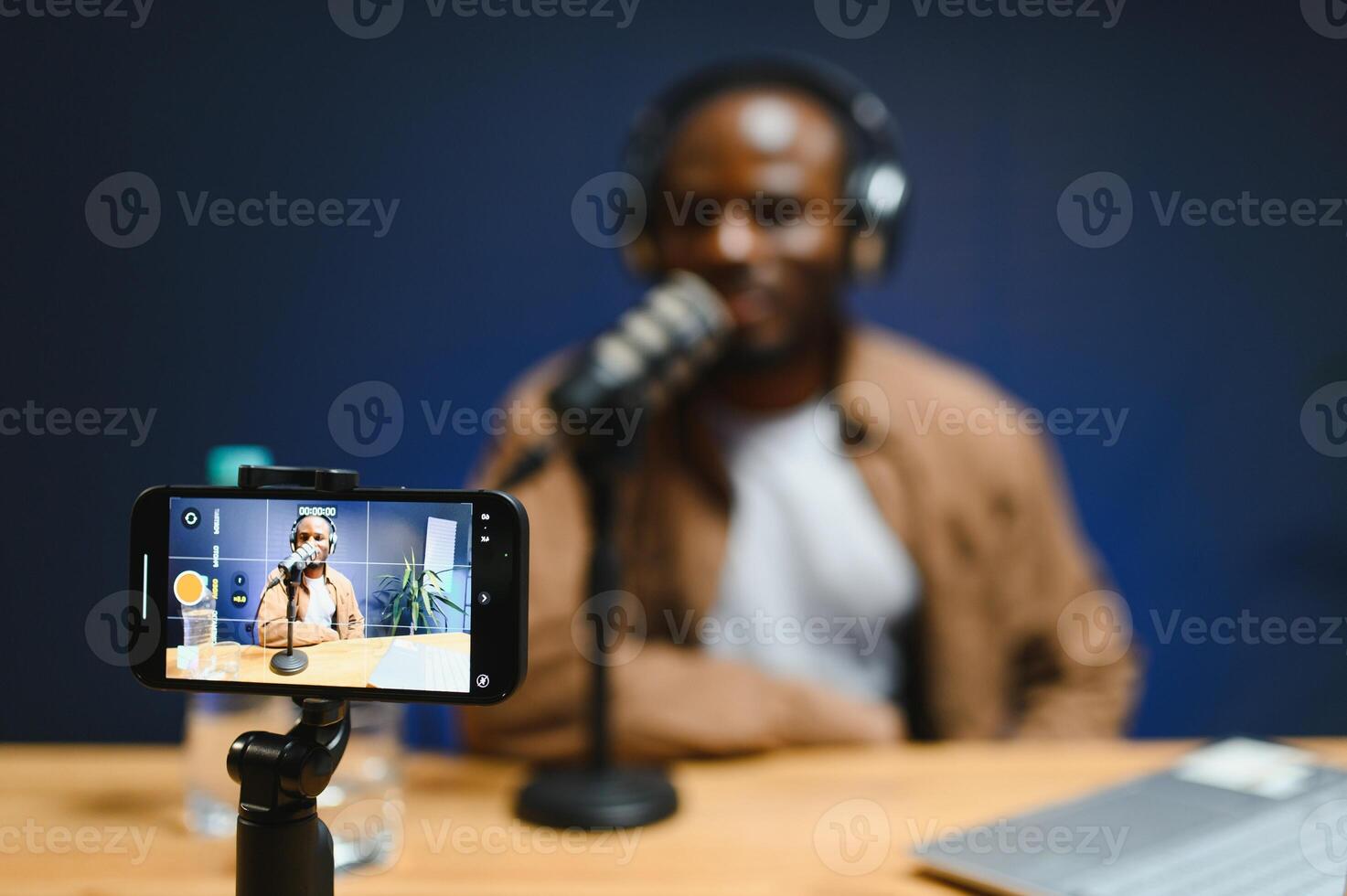 Young African American male vlogger influencer in headphones record blog on smartphone photo