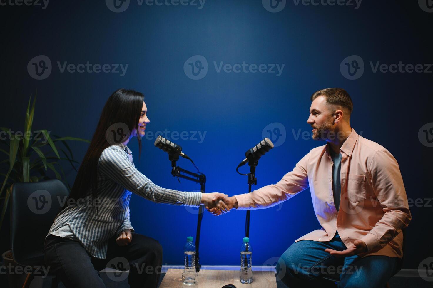 Happy podcasters man and woman shaking hands after recording podcast photo