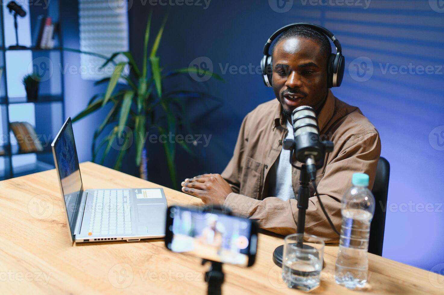 Young african american male vlogger recording blog in studio with professional microphone. photo