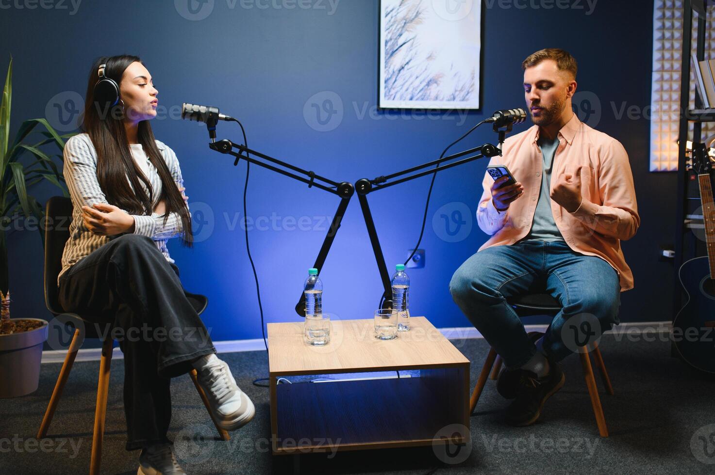 Side view of successful woman hosting podcast interviewing man while recording with professional microphones, copy space photo