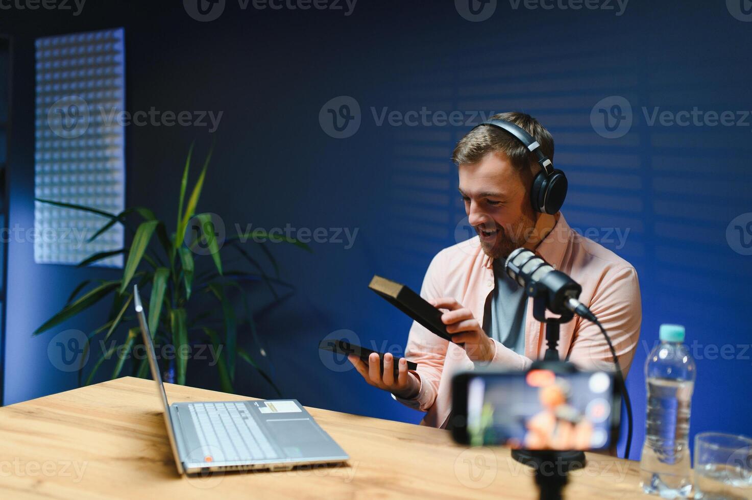 Joyful young man recording unboxing in studio photo