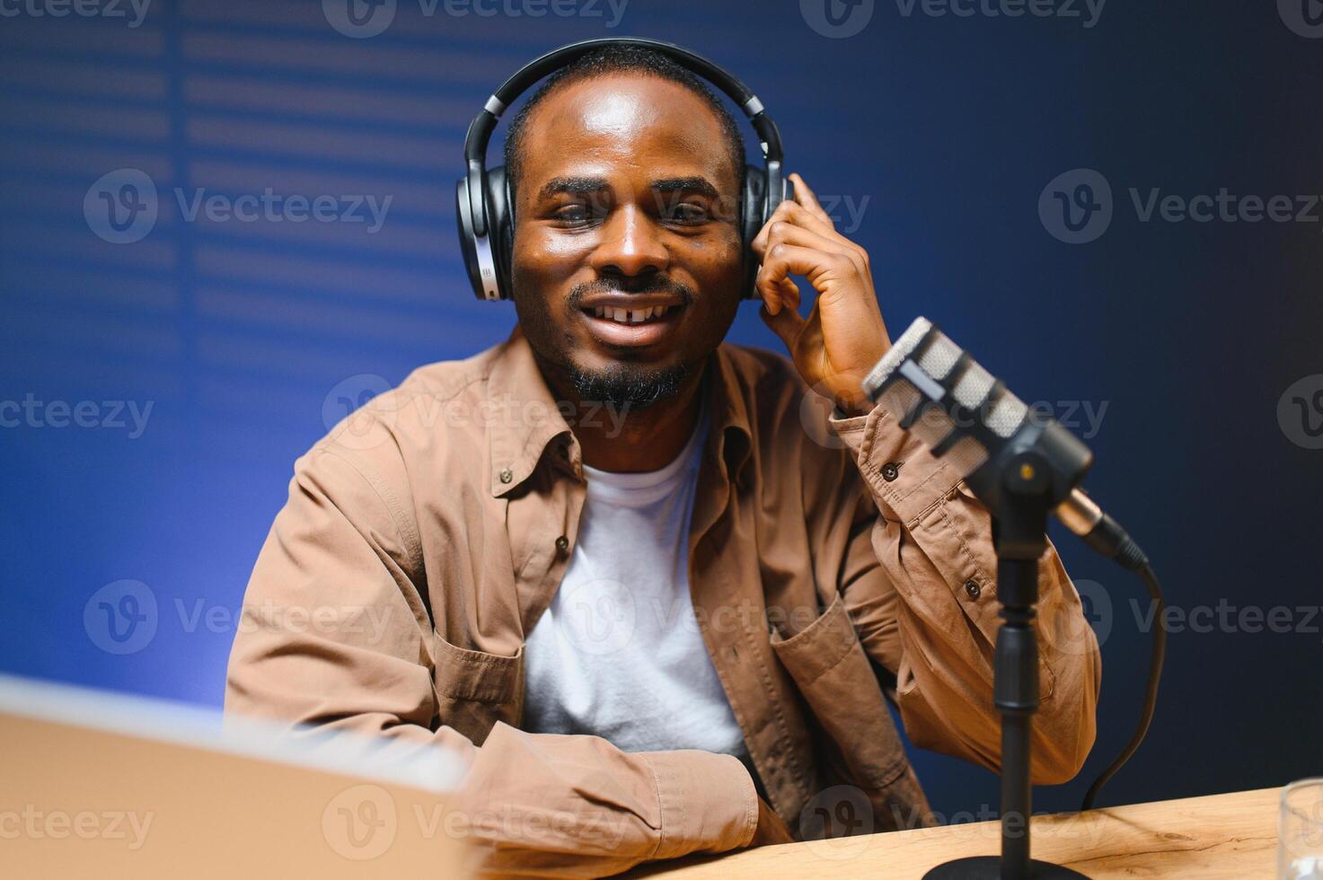 Black vlogger filming podcast on smartphone in studio. Cheerful blogger photo