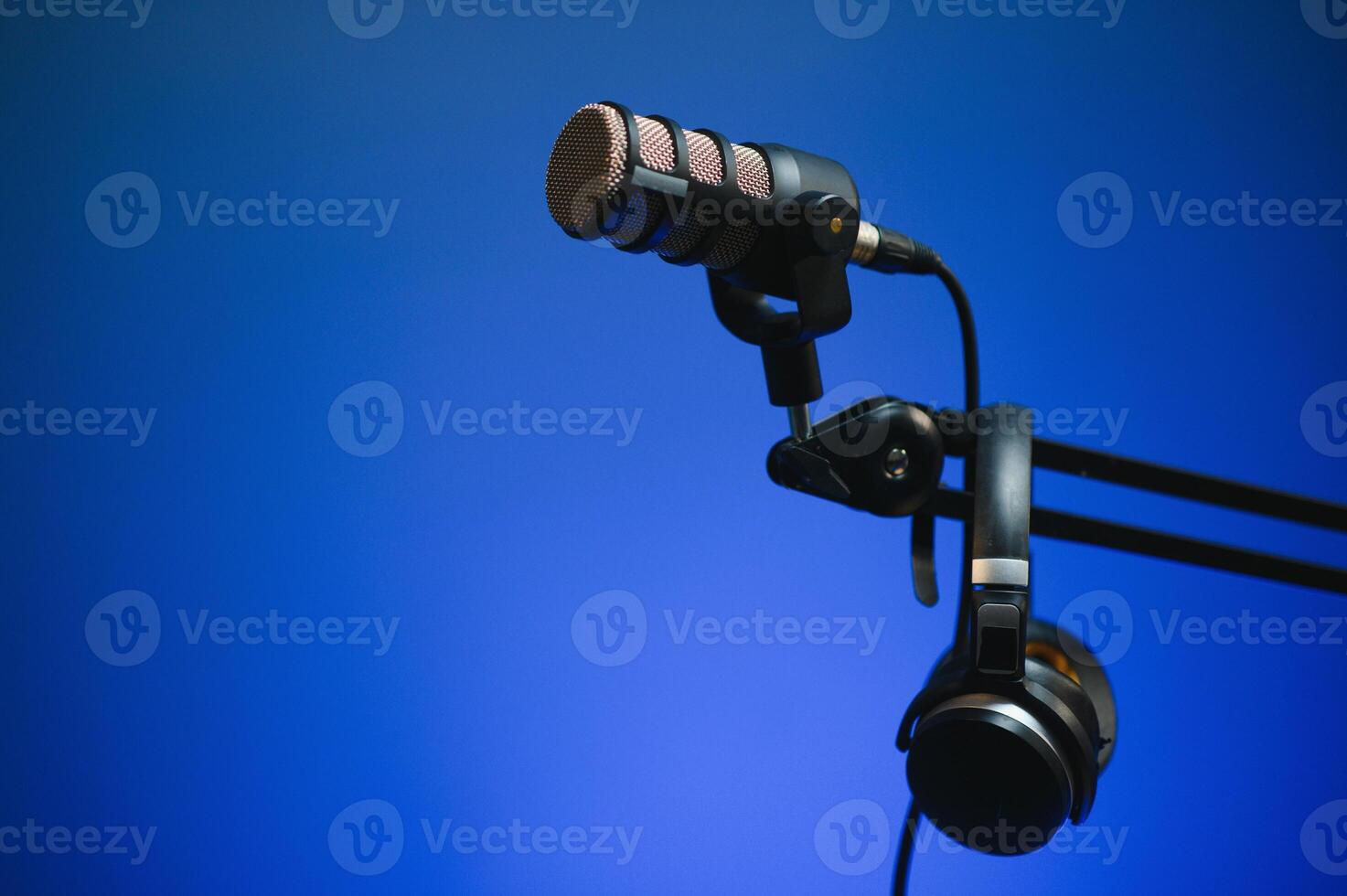 Close up shot of podcast microphone used to record conversations for internet livestreaming show. Streaming sound capturing and recording technology in empty home studio with neon lights photo