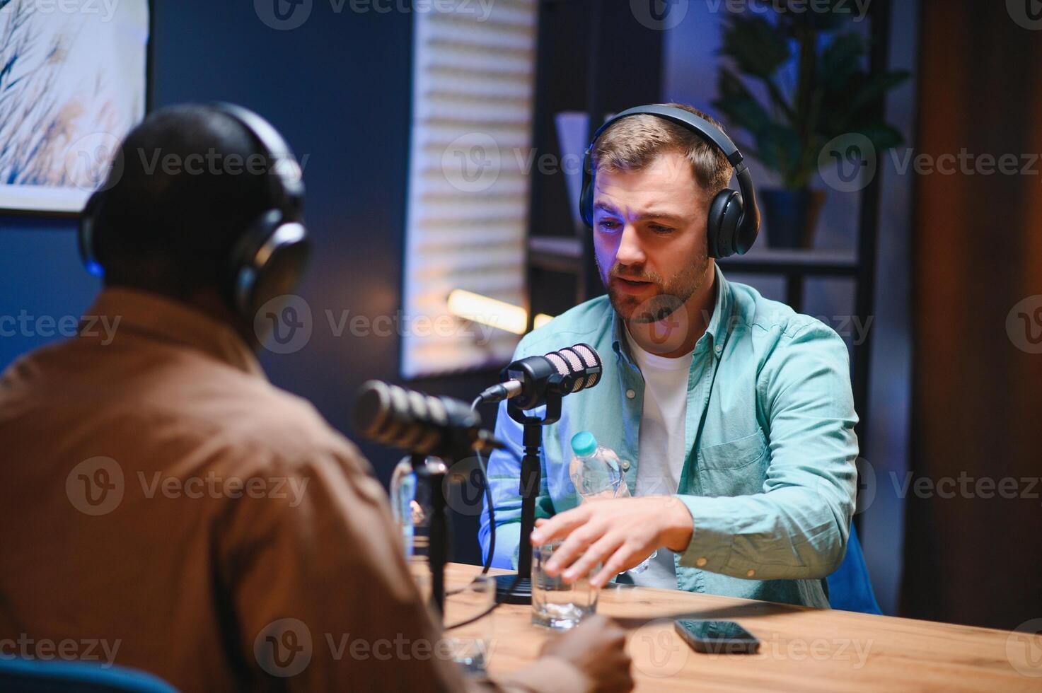 Show host and guest meeting to stream podcast episode together, creating online content with live broadcast discussion. Vlogger talking to man using professional equipment to record chat photo