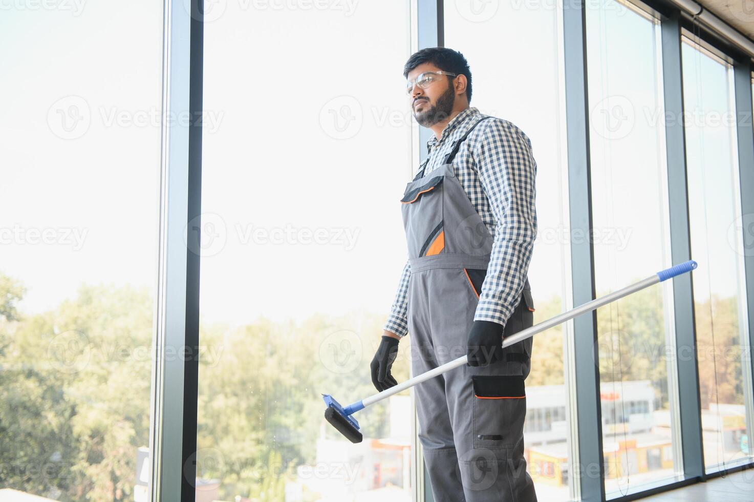 Male professional cleaning service worker cleans the windows and shop windows of a store with special equipment photo