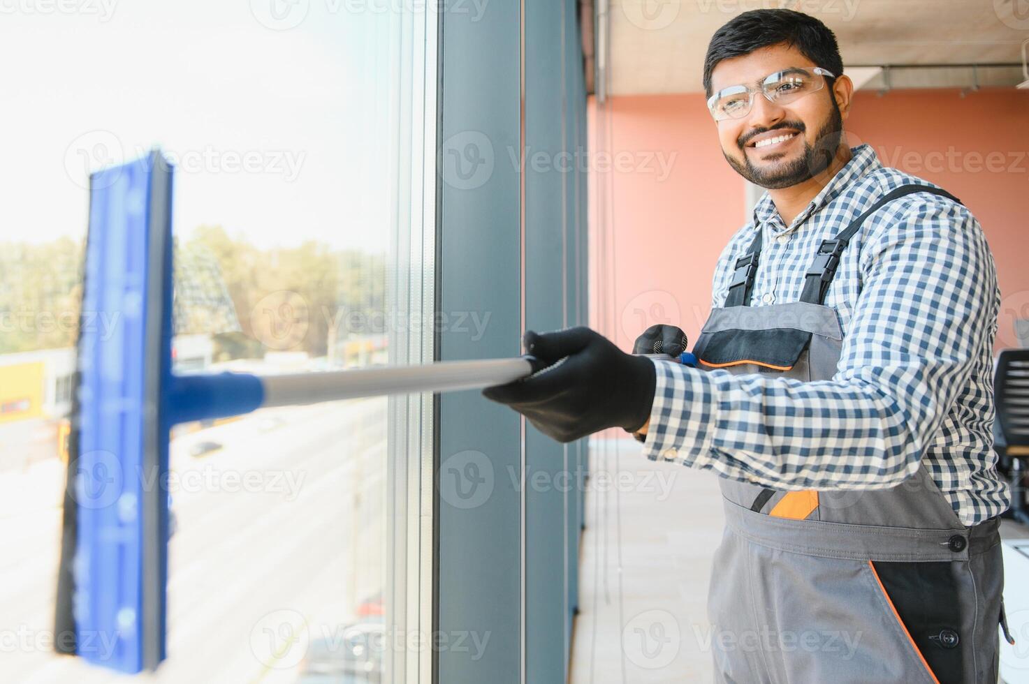 Male professional cleaning service worker cleans the windows and shop windows of a store with special equipment photo
