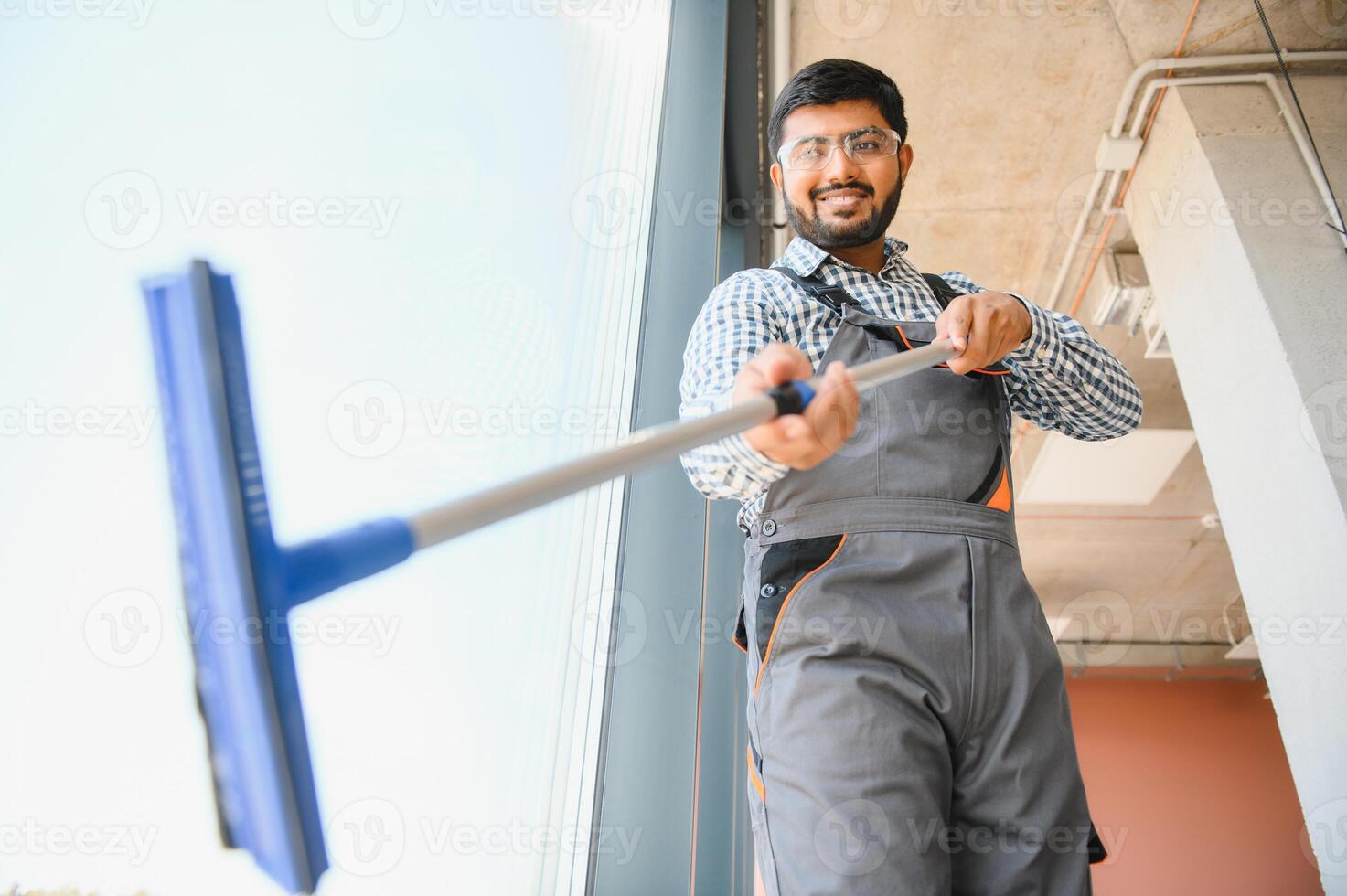 Male professional cleaning service worker cleans the windows and shop windows of a store with special equipment photo