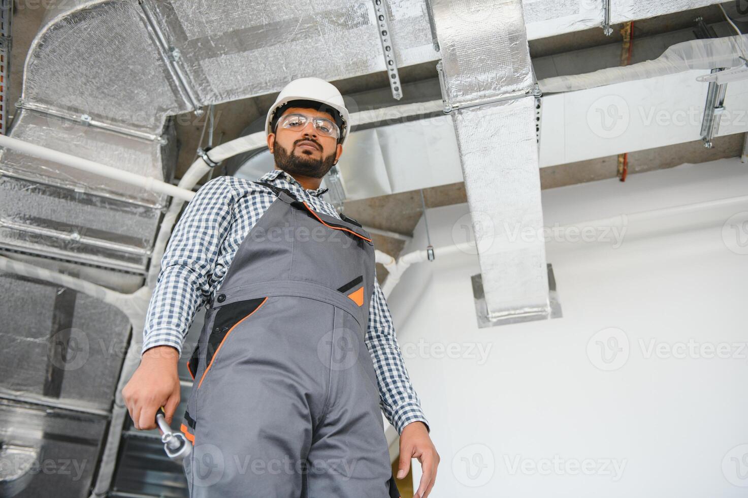 An Indian worker inspects the ventilation system in an office building photo