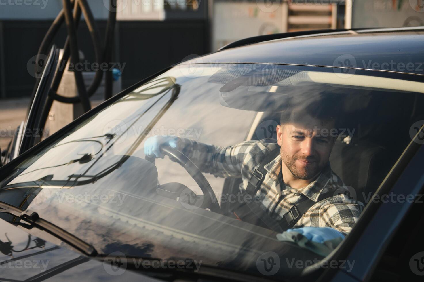 Feeling happy to be doing an excellent job at my job at the car wash. Portrait of a man while sitting inside a customer vehicle photo