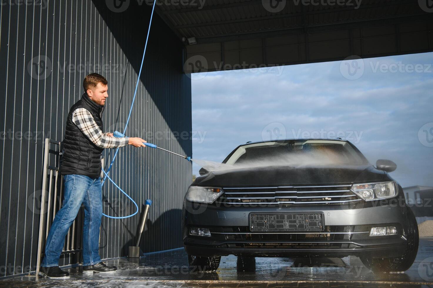 Car wash. Man washes car with water from high pressure washer photo